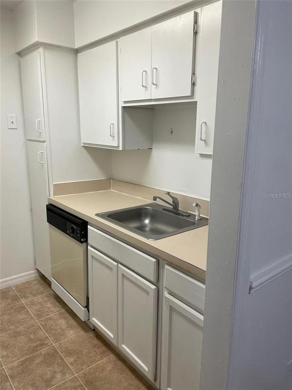 A small kitchen features white cabinets, a stainless steel sink, and a dishwasher — 315 WYMORE ROAD UNIT 104, ALTAMONTE SPRINGS, FL