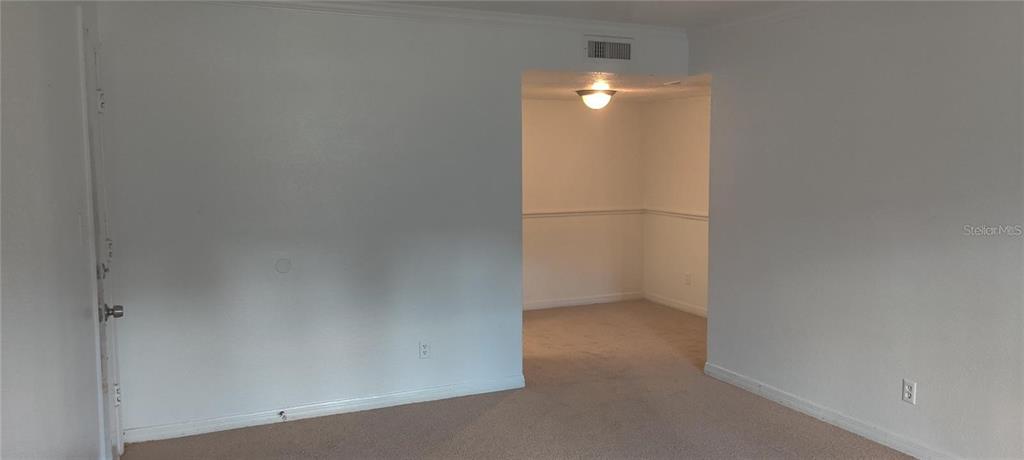 An interior view shows a carpeted room with white walls and a doorway to another area — 315 WYMORE ROAD UNIT 104, ALTAMONTE SPRINGS, FL
