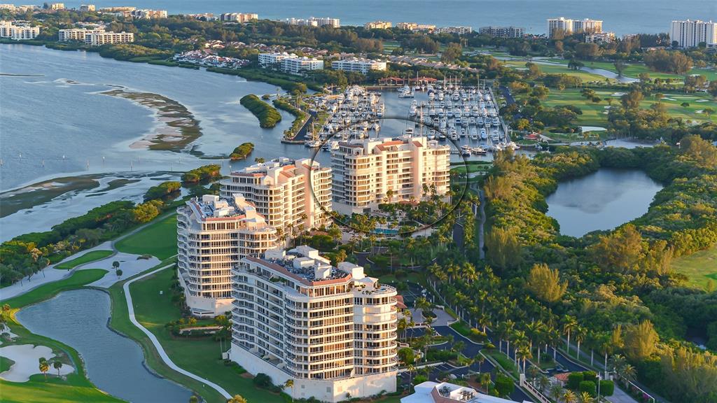 An aerial view shows high-rise residential buildings situated near a marina, golf course, and water — 3010 GRAND BAY BOULEVARD UNIT 493, LONGBOAT KEY, FL