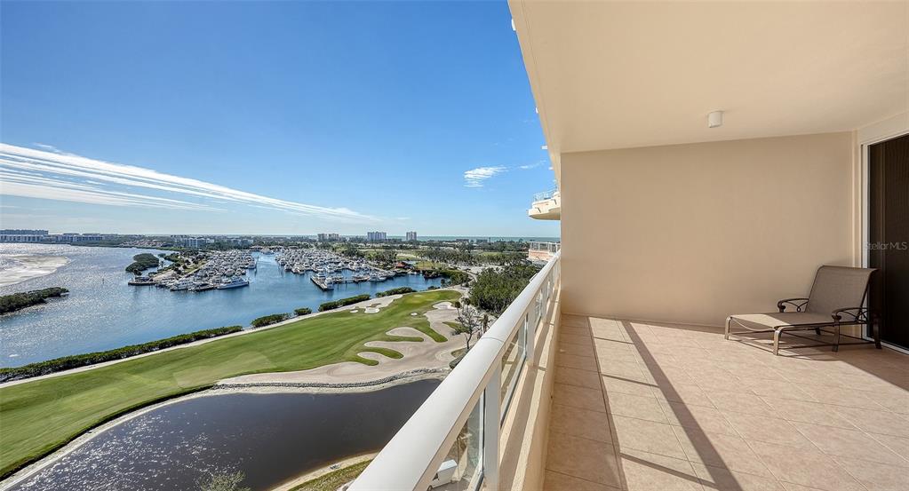 A balcony with tile flooring and a lounge chair overlooks a marina and golf course — 3010 GRAND BAY BOULEVARD UNIT 493, LONGBOAT KEY, FL