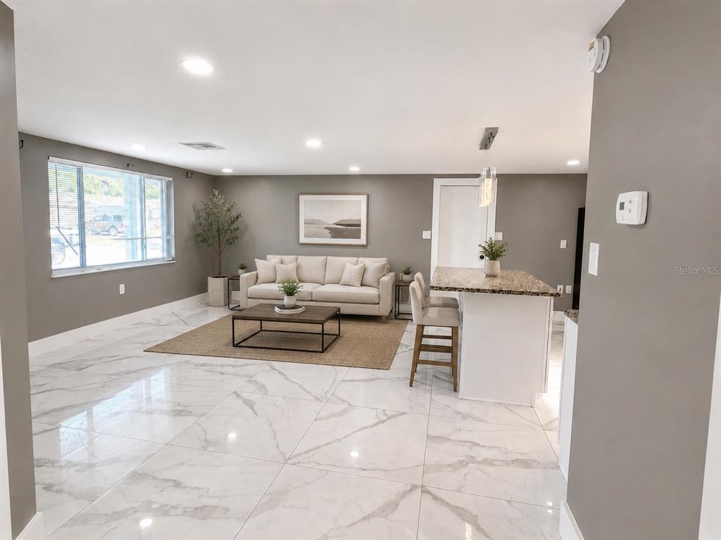 A living room with white marble floors, a beige sofa, and a granite kitchen island — 9015 PROSPERITY LANE, PORT RICHEY, FL