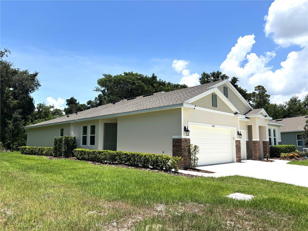 A single-story house with a beige stucco exterior, stone accents, and a two-car garage — 2168 GREENWOOD OAK DRIVE, OCOEE, FL