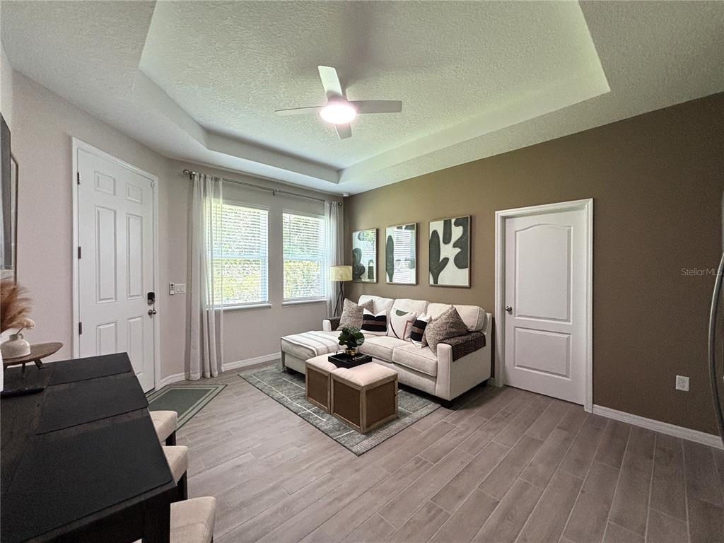 A living room features a tray ceiling, light wood-look tile flooring, and a beige sofa — 2168 GREENWOOD OAK DRIVE, OCOEE, FL
