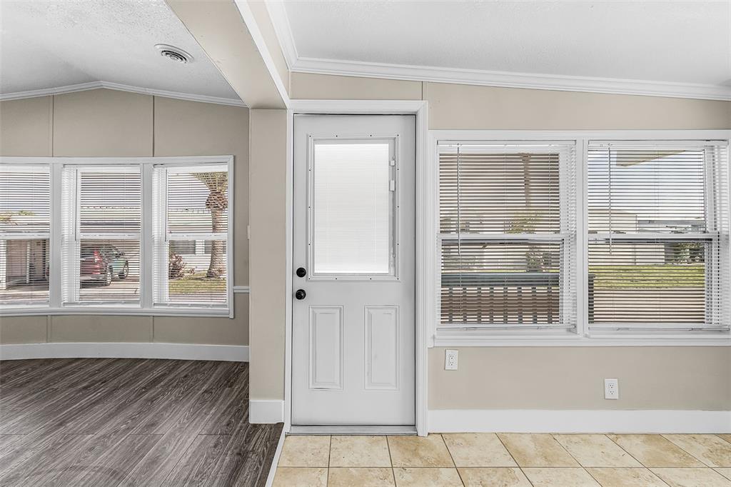 A room with wood-look flooring, tile, a white door, and windows with horizontal blinds — 1475 FLAMINGO DRIVE UNIT 385, ENGLEWOOD, FL