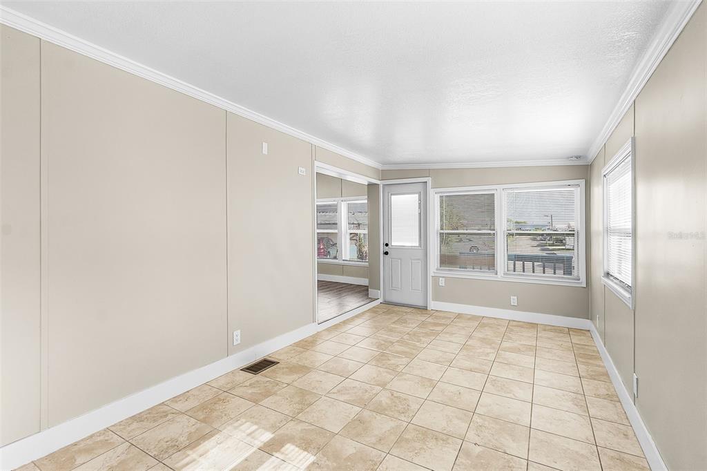 A room with beige walls, tile flooring, a white door, and windows with blinds — 1475 FLAMINGO DRIVE UNIT 385, ENGLEWOOD, FL