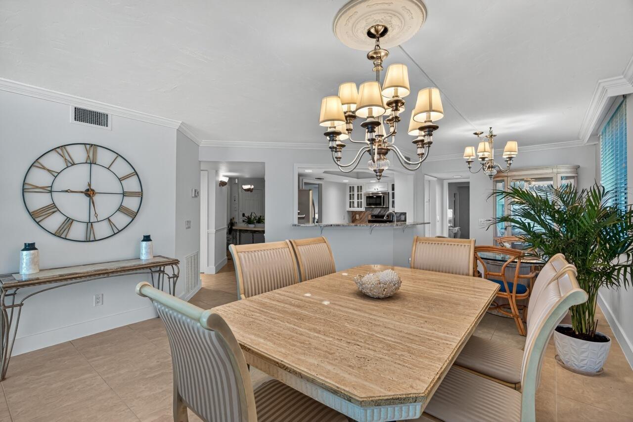 A dining room features a stone table, upholstered chairs, two chandeliers, and a large wall clock — 5790 Jimmy Buffett Mem Highway, Vero Beach FL 32963, VERO BEACH, FL
