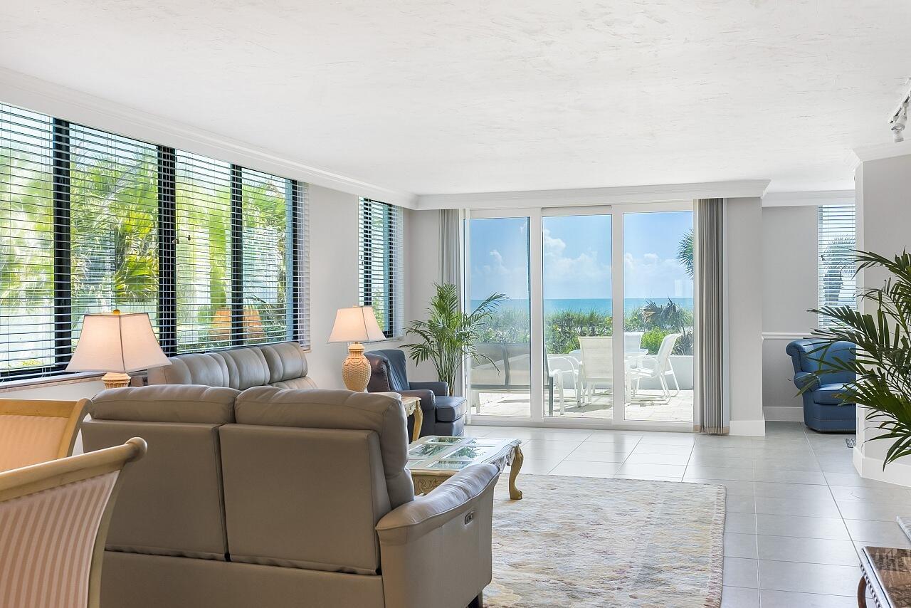 A living room with gray leather furniture, tile floors, and large windows overlooking the ocean — 5790 Jimmy Buffett Mem Highway, Vero Beach FL 32963, VERO BEACH, FL