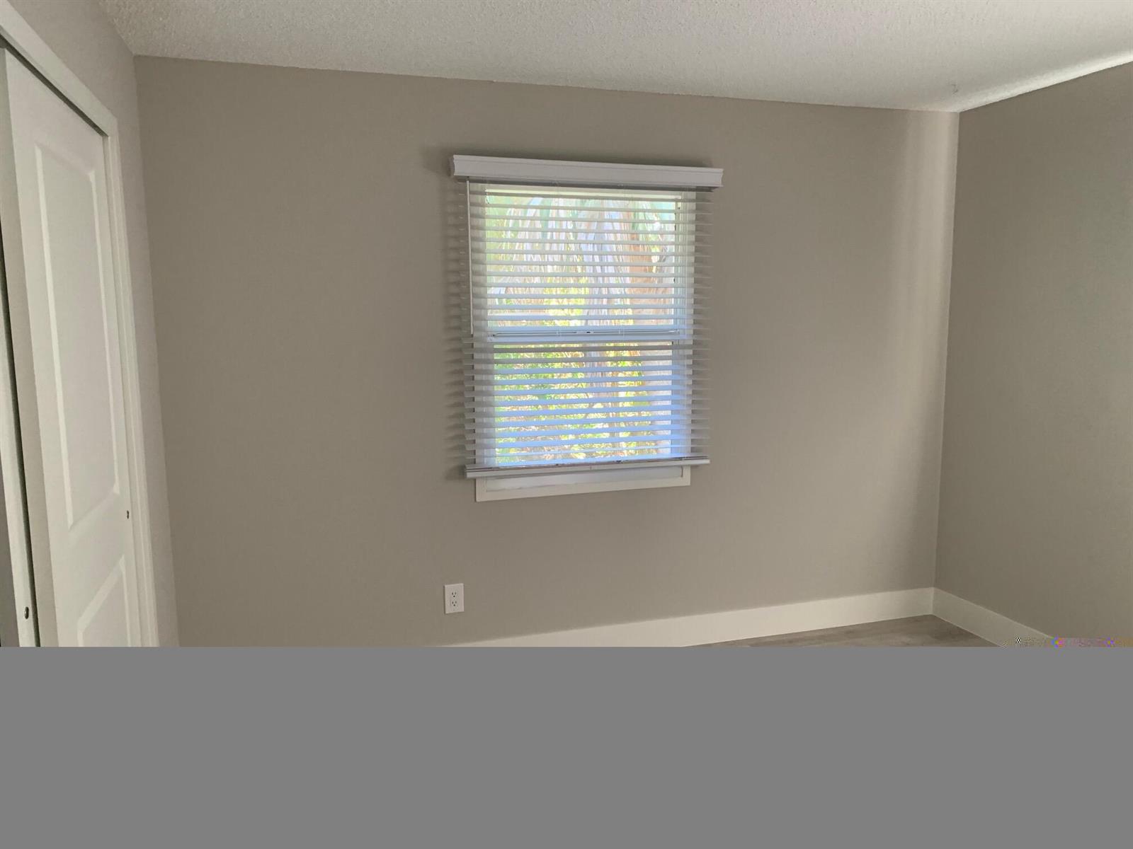 A bedroom with light gray walls, white trim, a window with blinds, and a closet — 4220 NE Indian River Drive NE Unit 5, Jensen Beach FL 34957, JENSEN BEACH, FL