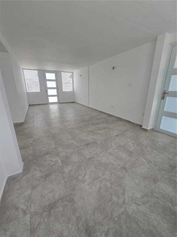 An empty room with gray tile flooring, white walls, and two white-framed glass doors — . HIGUERO UNIT P7, CAROLINA, PR