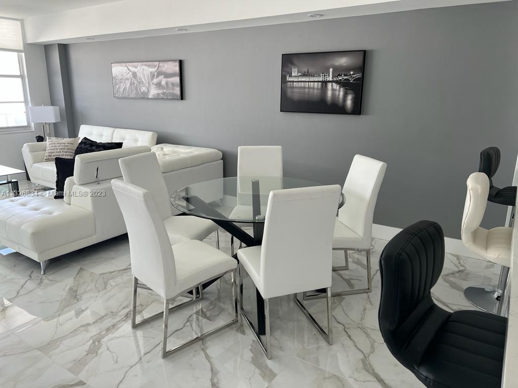 A modern living and dining area features white furniture, a glass table, and marble flooring — 3725 S Ocean Dr # 1503, Hollywood FL 33019, HOLLYWOOD, FL