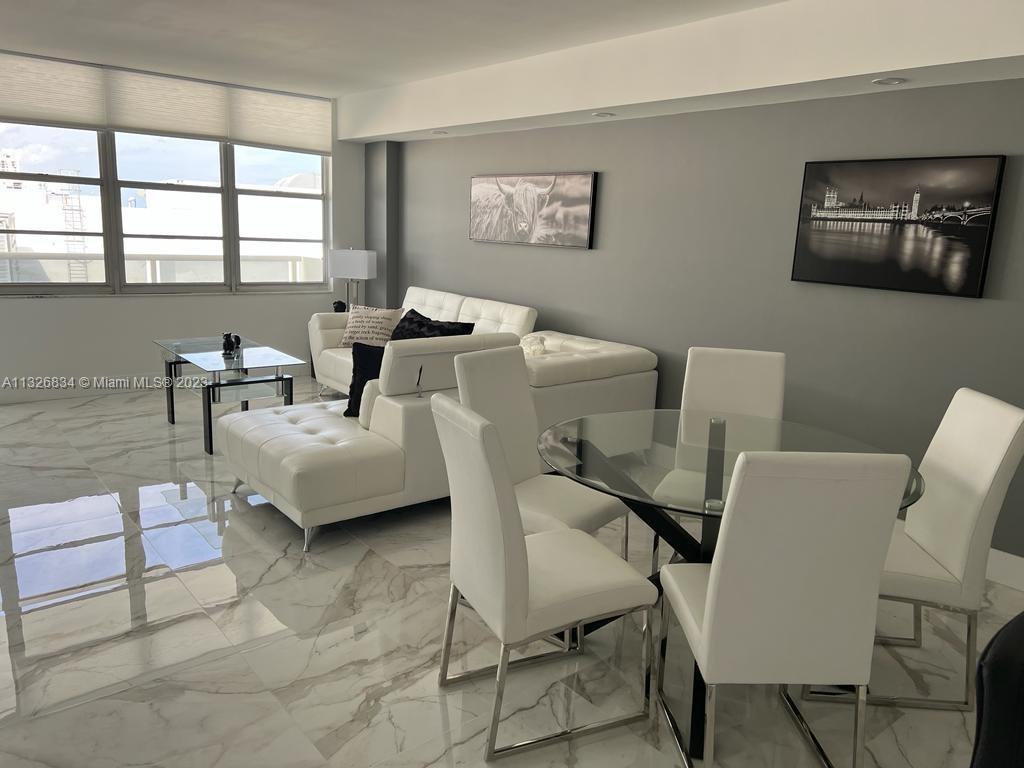 A modern living and dining area features white leather furniture, glass tables, and marble flooring — 3725 S Ocean Dr # 1503, Hollywood FL 33019, HOLLYWOOD, FL
