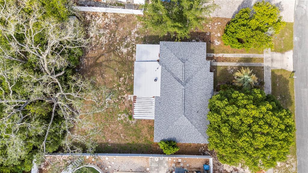 An aerial view shows a house with a gray shingled roof, a patio, and trees — 6816 TREEHAVEN DRIVE, SPRING HILL, FL