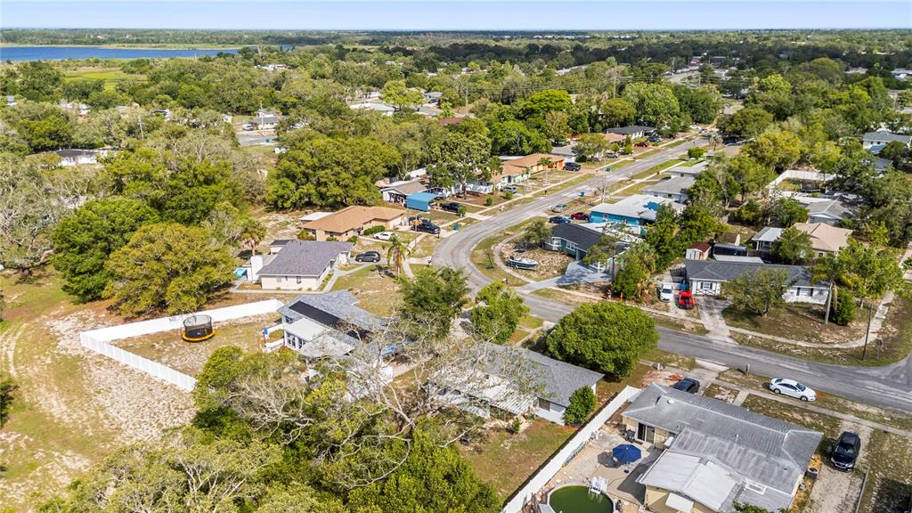 An aerial view shows a residential neighborhood with houses, trees, and a distant body of water — 6816 TREEHAVEN DRIVE, SPRING HILL, FL