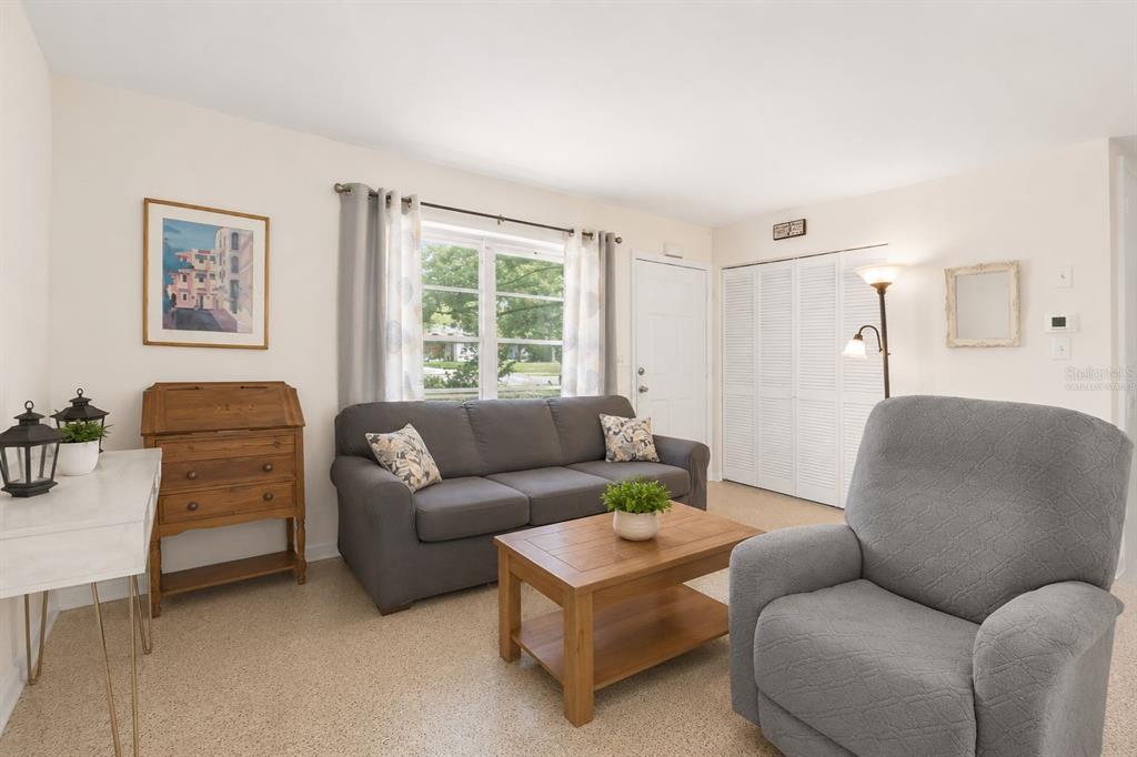 A living room features a gray sofa, a recliner, a wooden coffee table, and a desk — 6816 TREEHAVEN DRIVE, SPRING HILL, FL