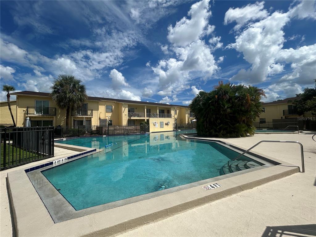 A swimming pool with a depth marker sits in front of a multi-story apartment building — 7502 BOLANOS COURT, TAMPA, FL