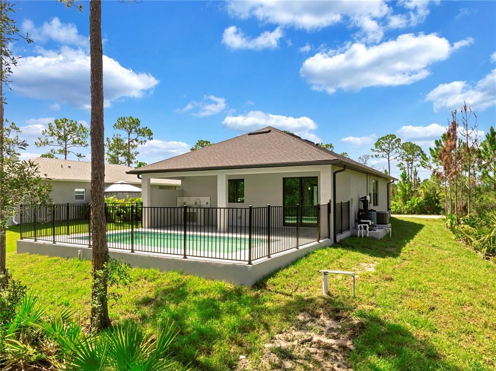 A backyard view of a house with a swimming pool enclosed by a black fence — 27412 LAS LOMAS DRIVE, PUNTA GORDA, FL