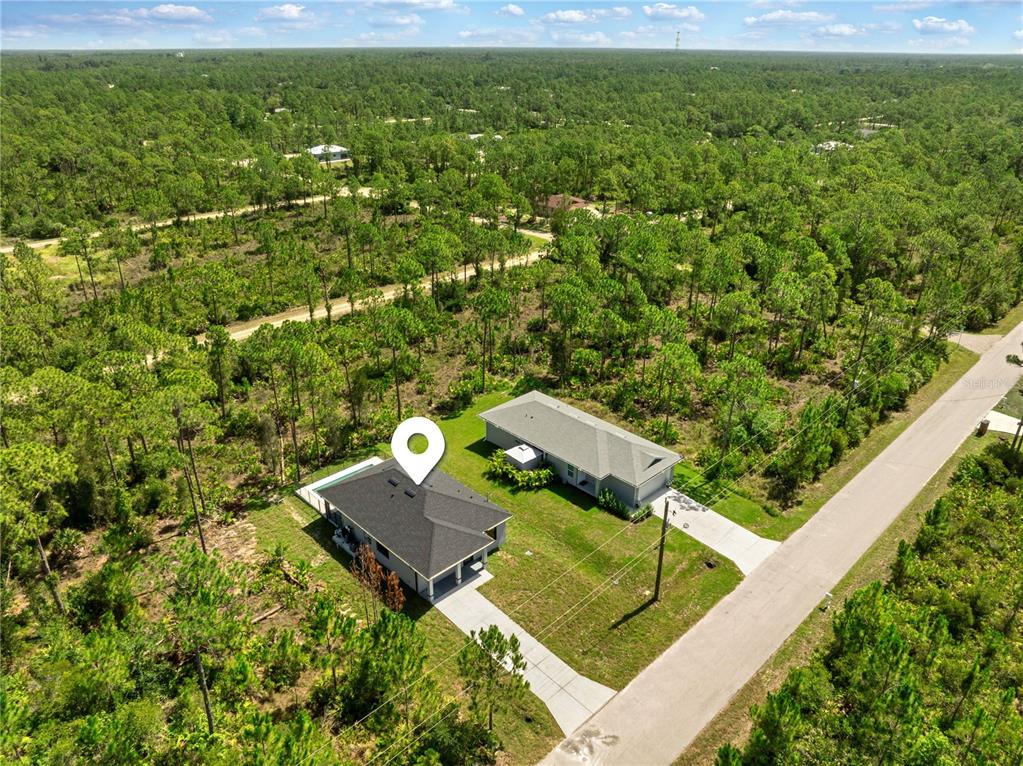 An aerial view shows a house with a dark roof and a neighboring home nearby — 27412 LAS LOMAS DRIVE, PUNTA GORDA, FL