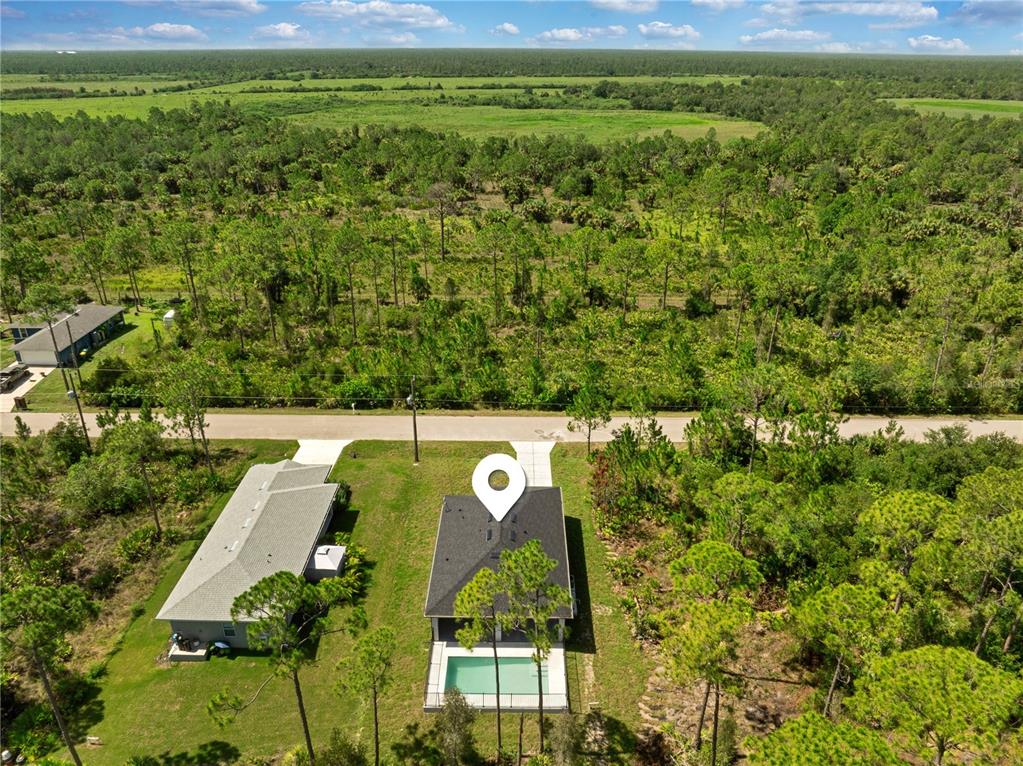 An aerial view shows a house with a pool and a large, wooded backyard — 27412 LAS LOMAS DRIVE, PUNTA GORDA, FL