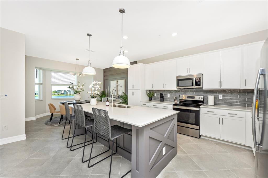 A kitchen features a gray island with bar seating, white cabinetry, and a gray backsplash — 12140 WELLEN GOLF STREET UNIT 401, VENICE, FL