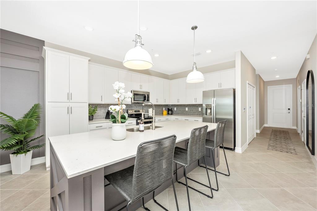 A kitchen features white cabinetry, a large gray island with bar seating, and stainless appliances — 12140 WELLEN GOLF STREET UNIT 401, VENICE, FL
