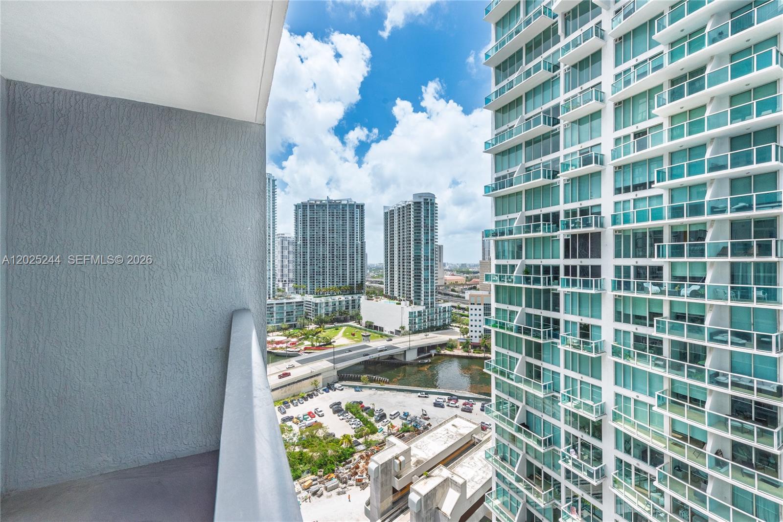 A balcony view overlooks a river, a bridge, and surrounding high-rise apartment buildings — 31 SE 6th St # 2506, Miami FL 33131, MIAMI, FL