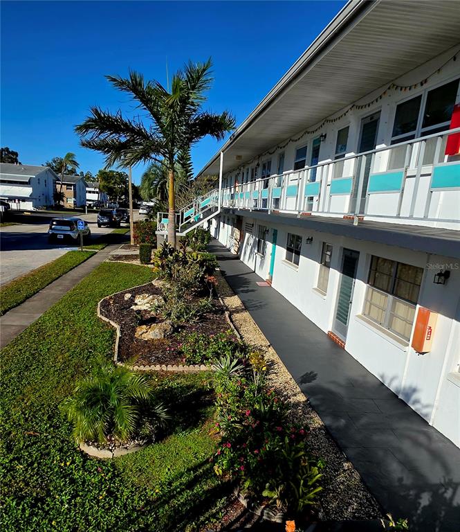 An exterior view of a multi-story apartment building with a walkway and landscaped garden area — 5945 21ST STREET N UNIT 18, ST PETERSBURG, FL