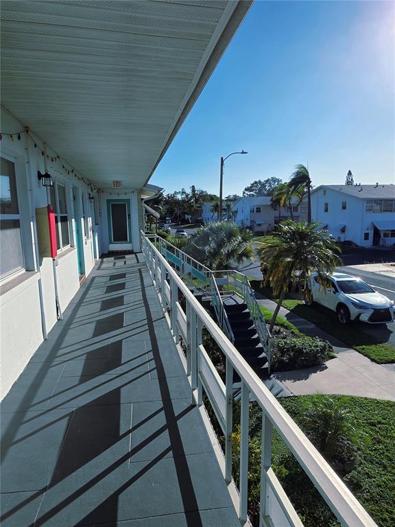 An elevated exterior walkway with a metal railing overlooks a parking area and palm trees — 5945 21ST STREET N UNIT 18, ST PETERSBURG, FL