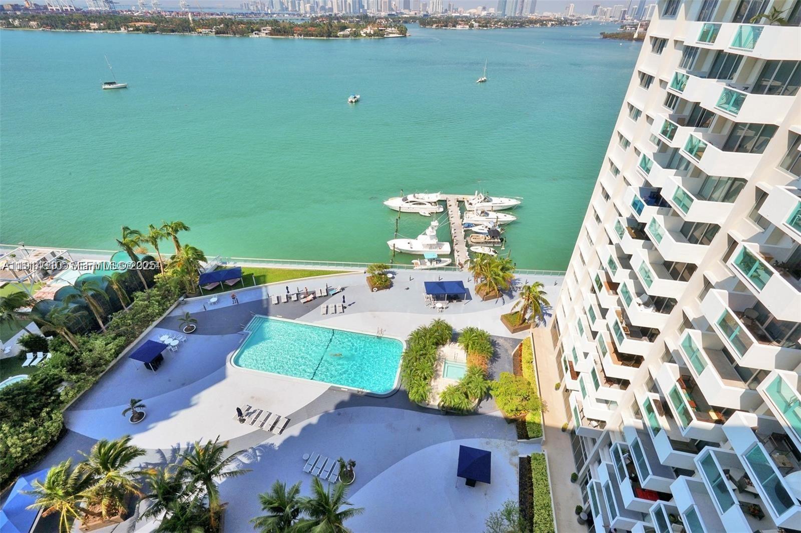 An aerial view shows a swimming pool, a boat dock, and a high-rise apartment building — 1200 West Ave # 1503, Miami Beach FL 33139, MIAMI BEACH, FL