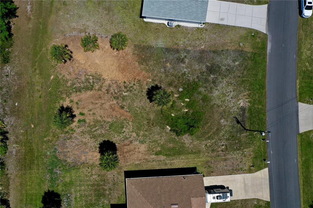 An aerial view shows a vacant residential lot situated between two houses and a road — 135 LONG MEADOW LANE, ROTONDA WEST, FL