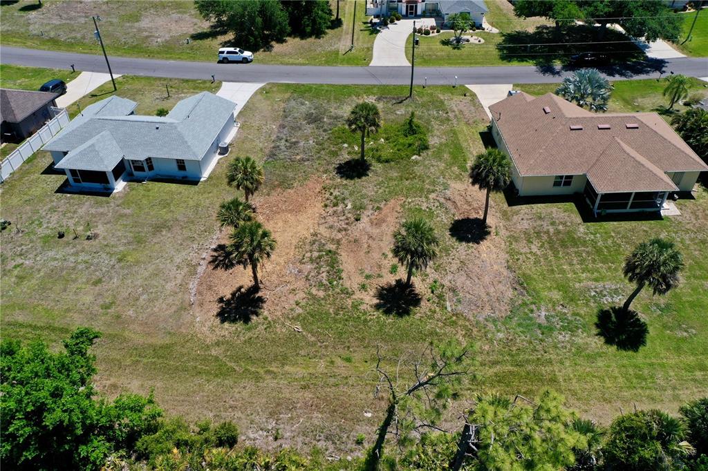 An aerial view shows a vacant residential lot situated between two single-family homes — 135 LONG MEADOW LANE, ROTONDA WEST, FL