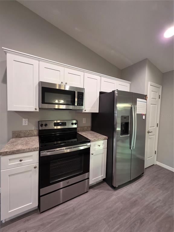 An open-concept kitchen and living area features light gray walls, recessed lighting, and wood-look flooring — 4244 SE 138TH STREET, SUMMERFIELD, FL
