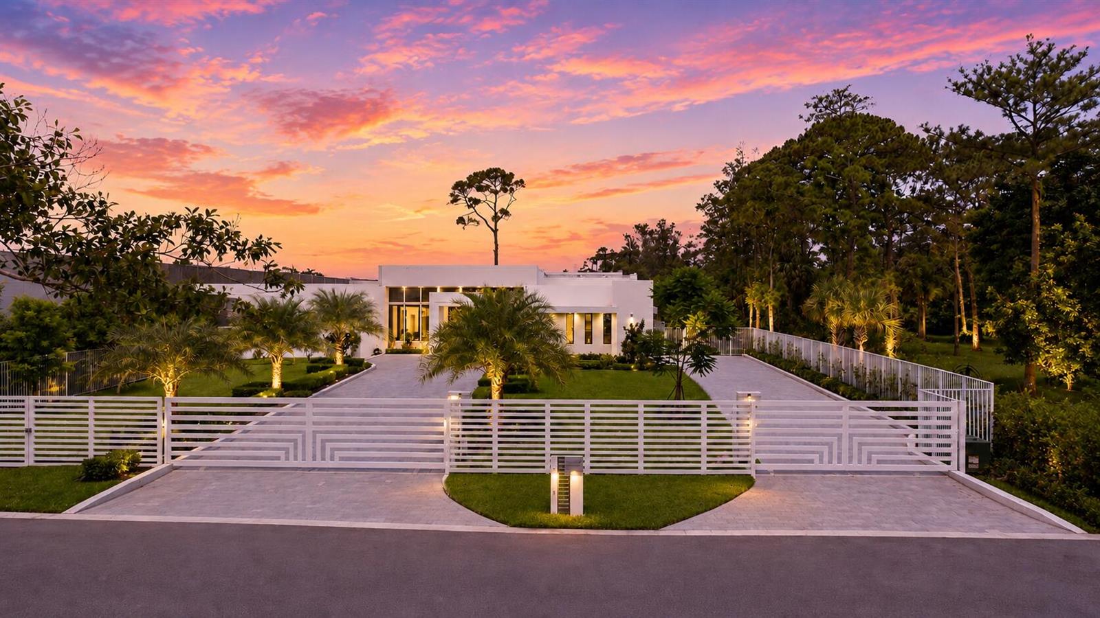 A white modern house with a gated driveway and palm trees at sunset — 5747 NW 63rd Way, Parkland FL 33067, PARKLAND, FL