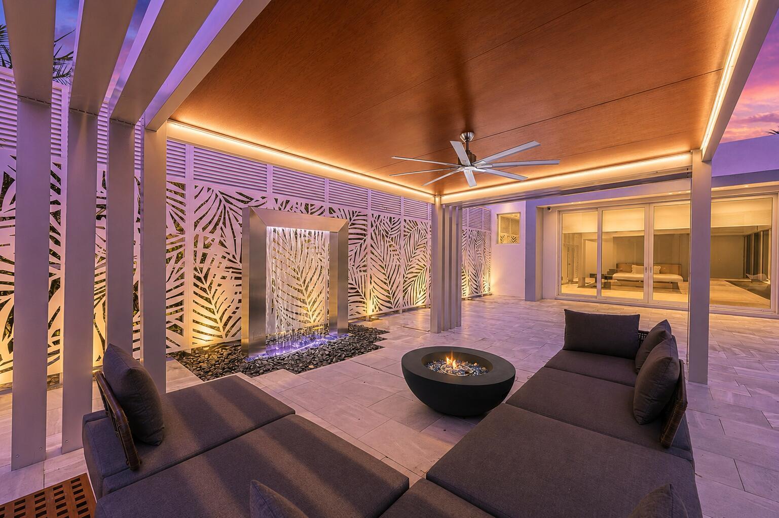 A modern outdoor patio features a fire pit, a water feature, and lounge seating under a pergola — 5747 NW 63rd Way, Parkland FL 33067, PARKLAND, FL