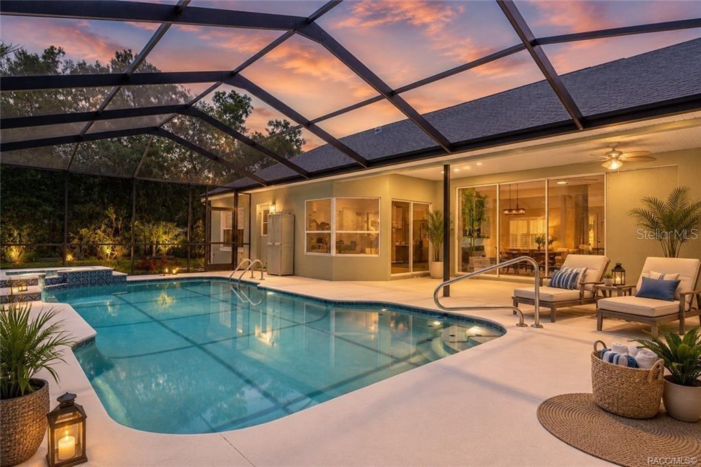 A screened-in swimming pool and patio area with lounge chairs at sunset — 1852 W IVORYWOOD DRIVE, BEVERLY HILLS, FL
