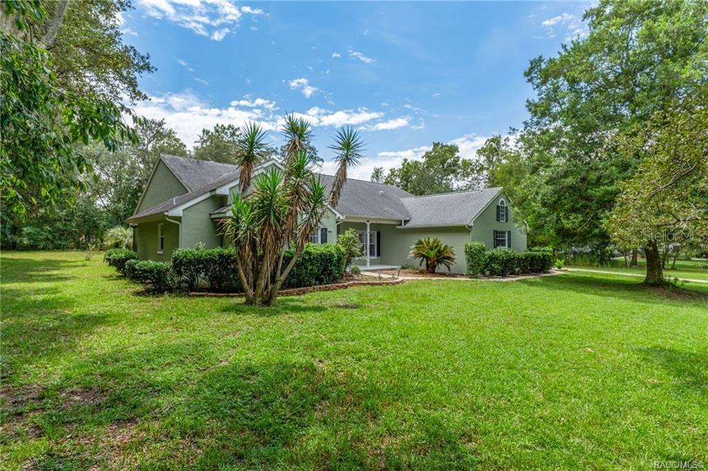 A green single-story house with a gray roof sits on a large, grassy lawn — 1852 W IVORYWOOD DRIVE, BEVERLY HILLS, FL