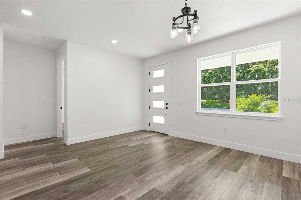 A bright room with wood-look flooring, a modern chandelier, a white front door, and windows — 321 WATER SHORE DRIVE, LEESBURG, FL