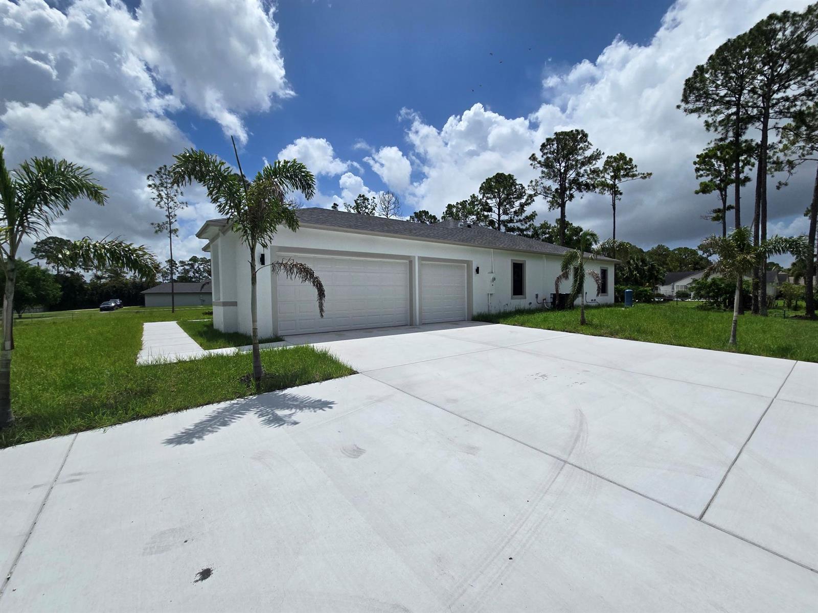A white single-story house features a three-car garage and a large concrete driveway — 14974 N 77th Pl Place N, Loxahatchee FL 33470, LOXAHATCHEE, FL