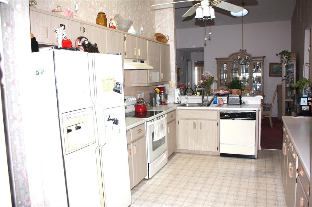 A kitchen with light wood cabinets, white appliances, and a vinyl floor — 18 BRISTOL DRIVE, PALM COAST, FL