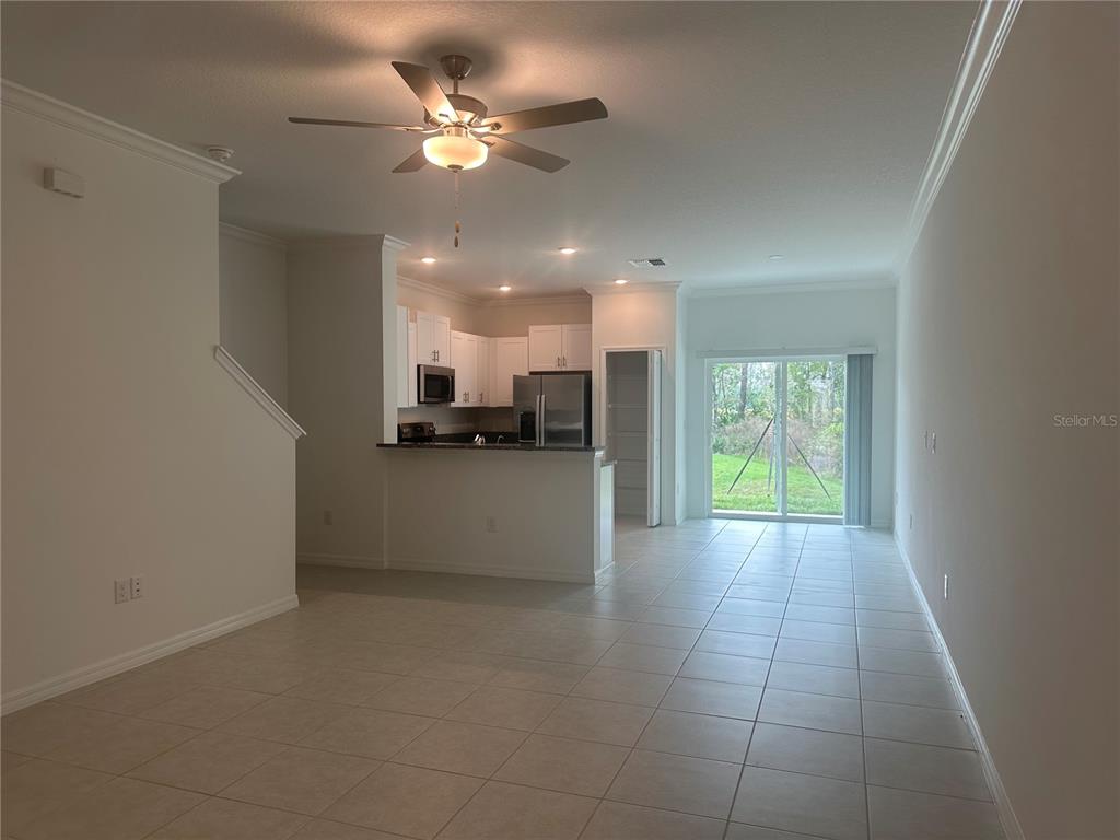 An open-concept living area features tile flooring, a ceiling fan, and a kitchen with white cabinets — 17664 NECTAR FLUME DRIVE, LAND O LAKES, FL