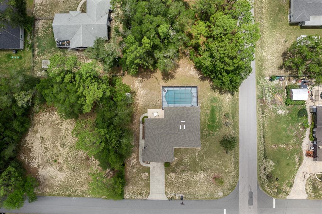 An aerial view shows a house with a screened-in pool on a wooded residential lot — 5216 E HOPP LANE, INVERNESS, FL