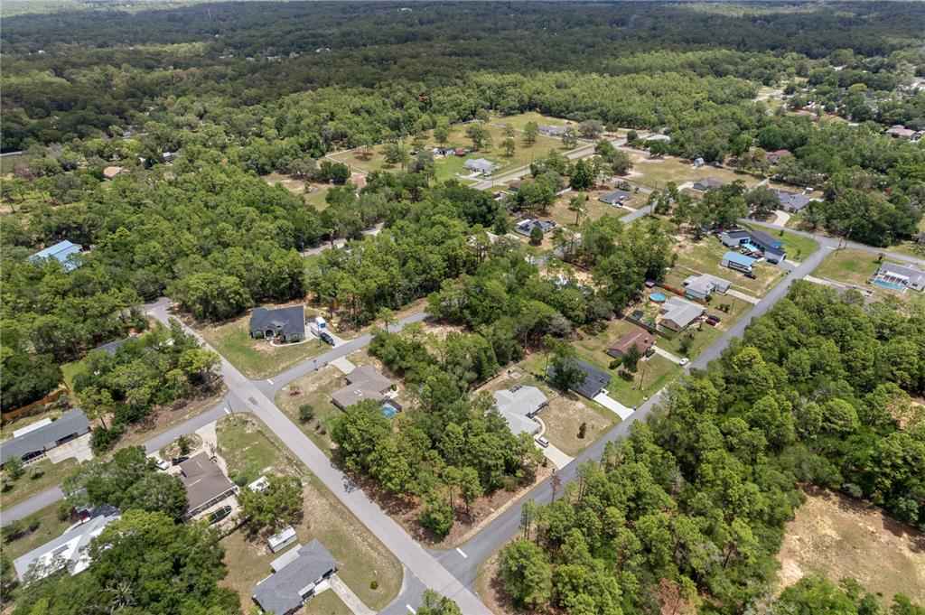 An aerial view shows several houses situated among dense trees and paved residential streets — 5216 E HOPP LANE, INVERNESS, FL