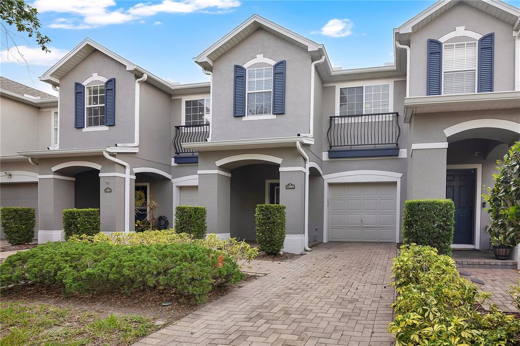A row of gray two-story townhomes with blue shutters and brick paver driveways — 12009 GREAT COMMISSION WAY, ORLANDO, FL