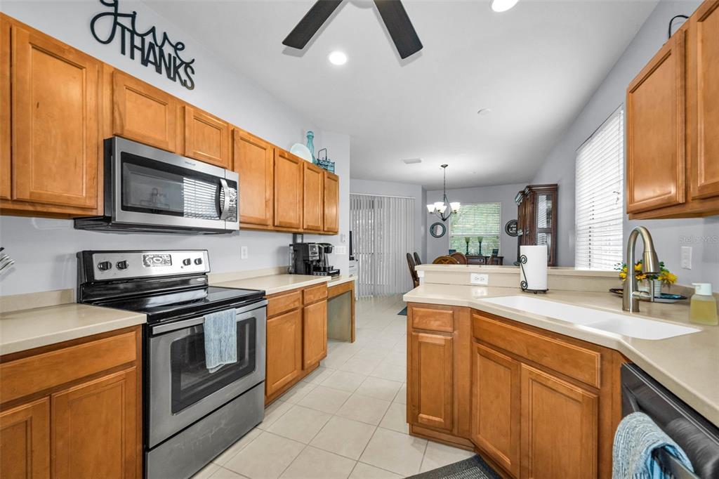 A kitchen features wood cabinets, stainless steel appliances, a double sink, and tile flooring — 889 LANTERN WAY, CLEARWATER, FL