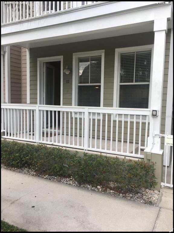 A front porch with white railings and two windows on a green-sided house exterior — 2002 E 5TH AVENUE UNIT 112, TAMPA, FL