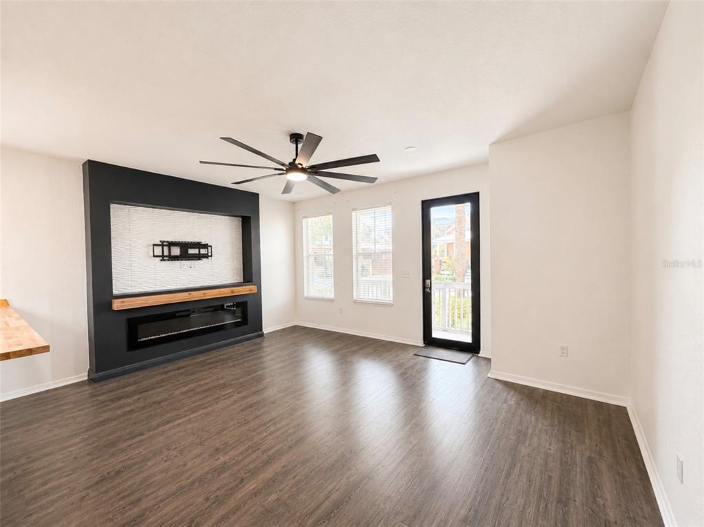 A living room features dark wood-look flooring, a black accent wall with a fireplace, and windows — 2002 E 5TH AVENUE UNIT 112, TAMPA, FL