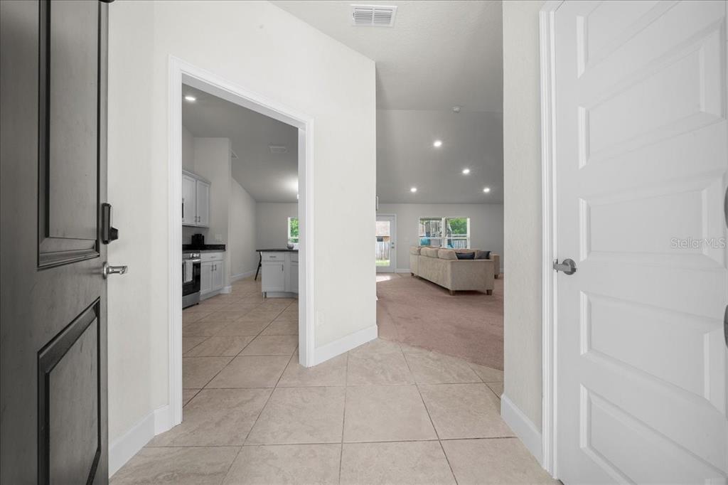A tiled entryway leads into a kitchen and a carpeted living area with vaulted ceilings — 97 DOGWOOD DRIVE LOOP, OCALA, FL