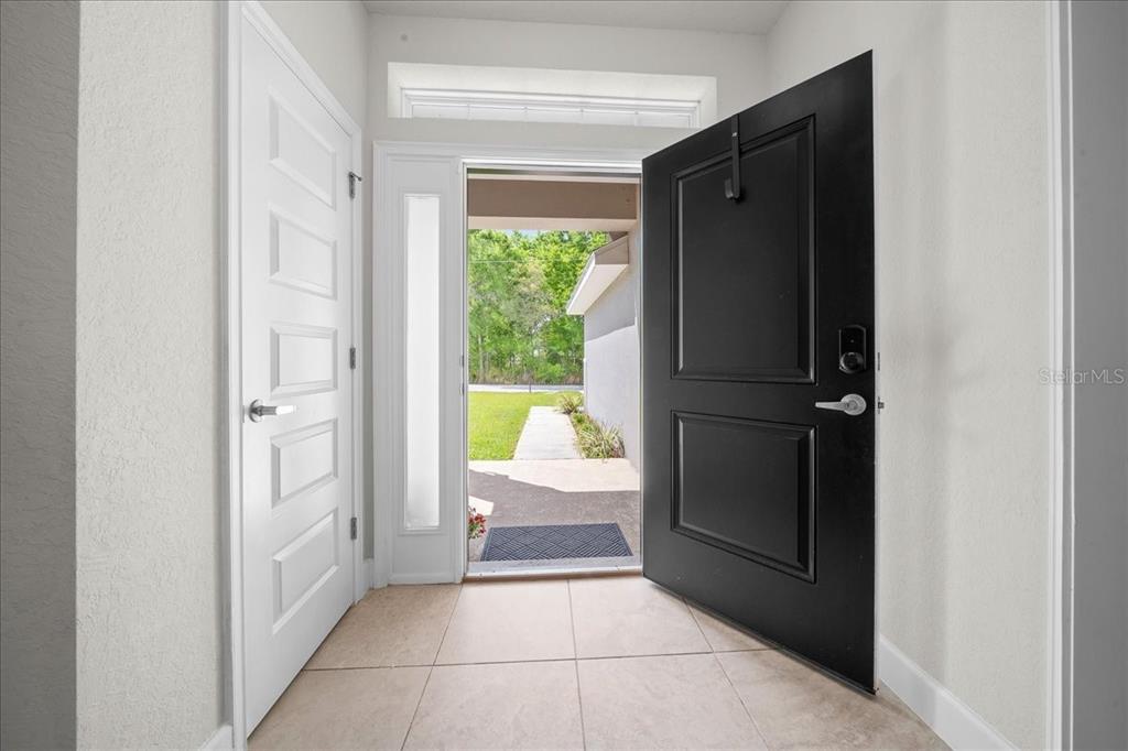 An entryway features a black front door, a white interior door, and light-colored tile flooring — 97 DOGWOOD DRIVE LOOP, OCALA, FL