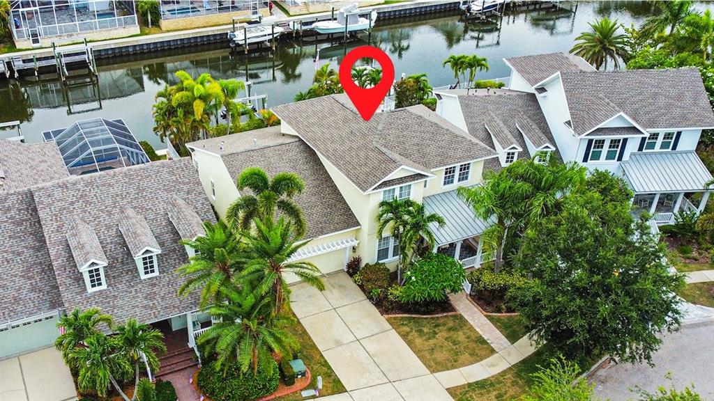 An aerial view shows a waterfront house with a shingled roof and palm trees — 432 ISLEBAY DRIVE, APOLLO BEACH, FL