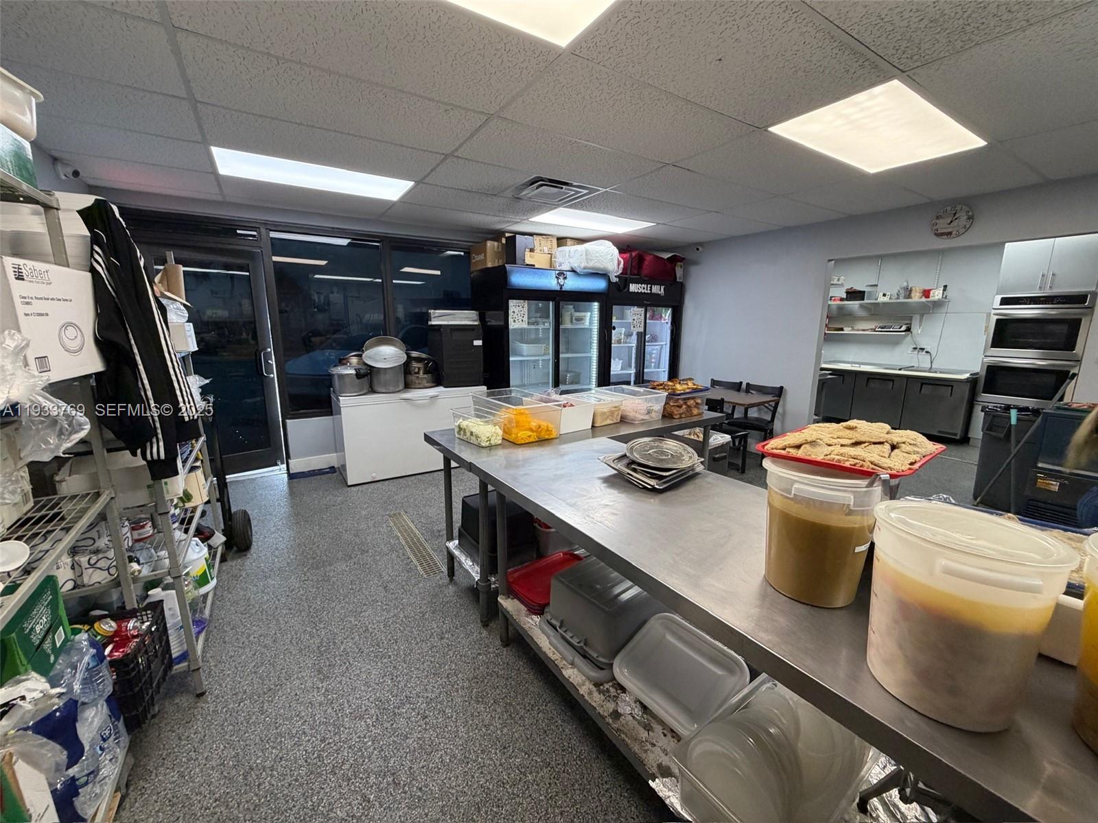 A commercial kitchen features stainless steel prep tables, storage shelving, and various food containers — for sale SW restaurant, Miami FL 33166, MIAMI, FL