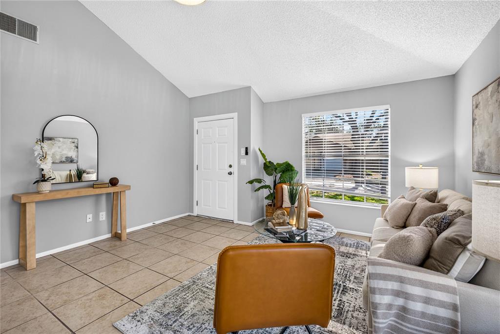 A living room features light gray walls, tile flooring, a vaulted ceiling, and a front door — 3610 SAMMY COURT, PALM HARBOR, FL